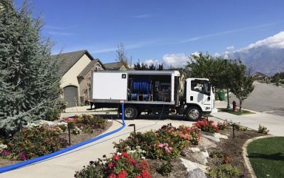 Wide Angle Shot Of A White Truck With Water And Electricity Lines Leading Into A House For Carpet Cleaning Services
